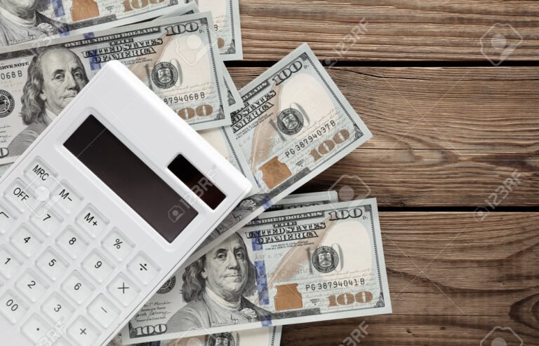 calculadora y billetes sobre mesa de madera