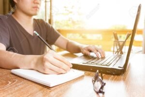 persona firmando documentos con laptop abierta